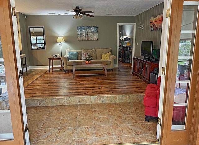 living room featuring ceiling fan, a textured ceiling, and wood-type flooring