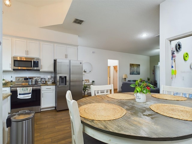 kitchen with dark wood-type flooring, tasteful backsplash, stainless steel appliances, and white cabinets