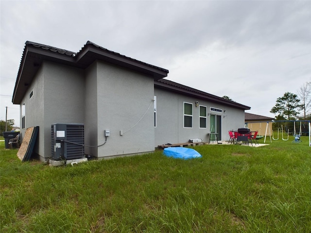 back of property featuring central air condition unit and a lawn