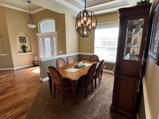 dining space featuring ornamental molding, hardwood / wood-style floors, an inviting chandelier, and a raised ceiling