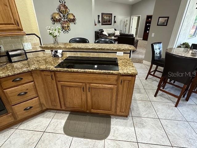 kitchen with light tile patterned flooring, light stone counters, and backsplash