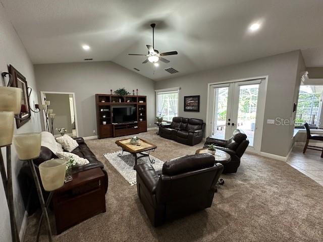 carpeted living room with lofted ceiling, french doors, and ceiling fan