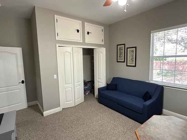 living area with light colored carpet and ceiling fan