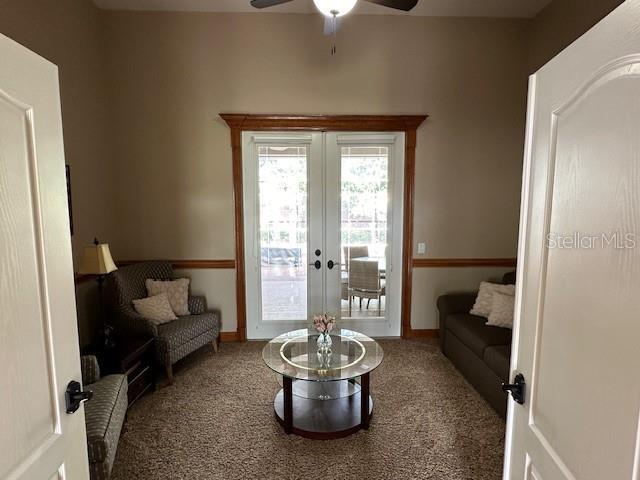 carpeted living room with ceiling fan and french doors