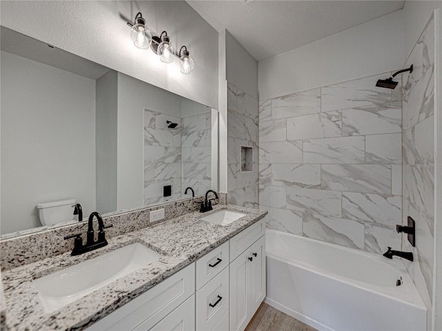 full bathroom featuring tiled shower / bath, dual bowl vanity, and toilet