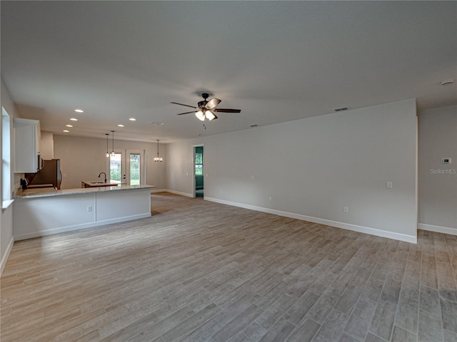 unfurnished living room with ceiling fan, light hardwood / wood-style flooring, and sink