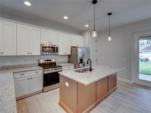 kitchen featuring appliances with stainless steel finishes, an island with sink, sink, white cabinetry, and light hardwood / wood-style flooring