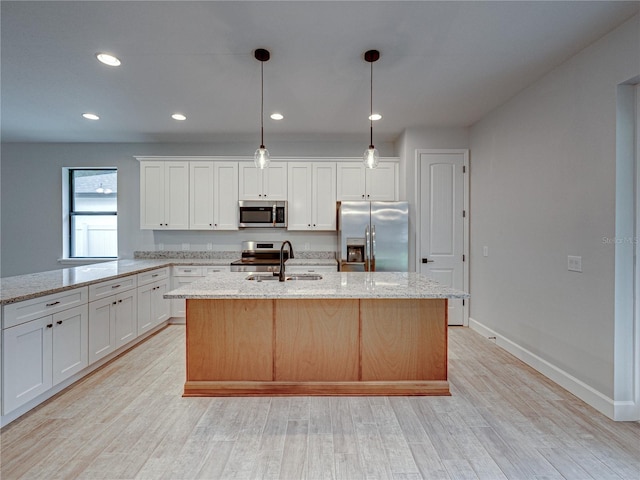 kitchen featuring light wood-type flooring, stainless steel appliances, light stone countertops, white cabinetry, and sink