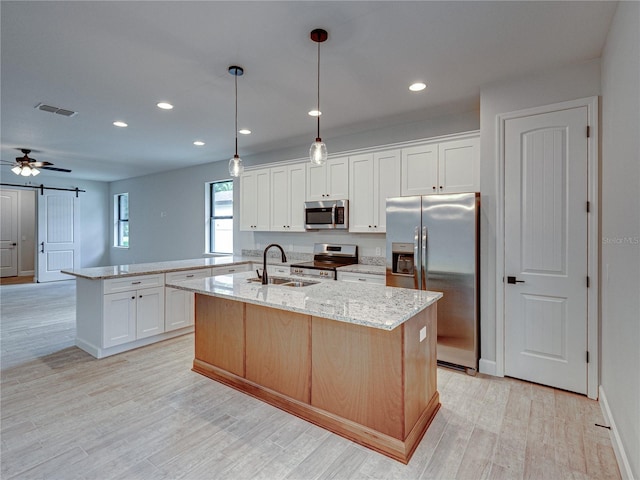 kitchen featuring stainless steel appliances, an island with sink, and white cabinetry