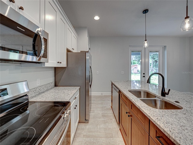 kitchen with light stone counters, sink, stainless steel appliances, and white cabinetry