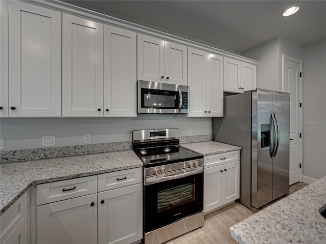 kitchen with light hardwood / wood-style flooring, white cabinets, stainless steel appliances, and light stone countertops