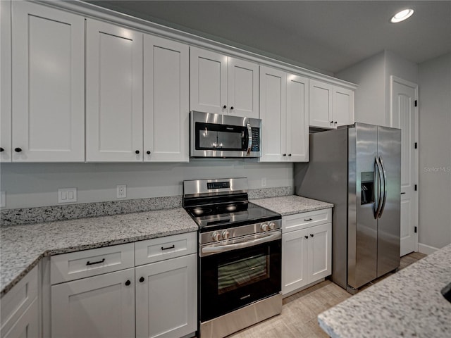 kitchen featuring white cabinetry, appliances with stainless steel finishes, light stone countertops, and light hardwood / wood-style flooring