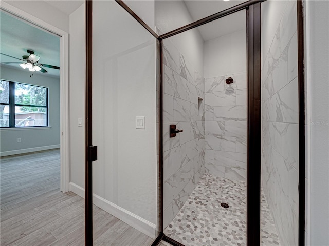 bathroom with a tile shower, ceiling fan, and wood-type flooring