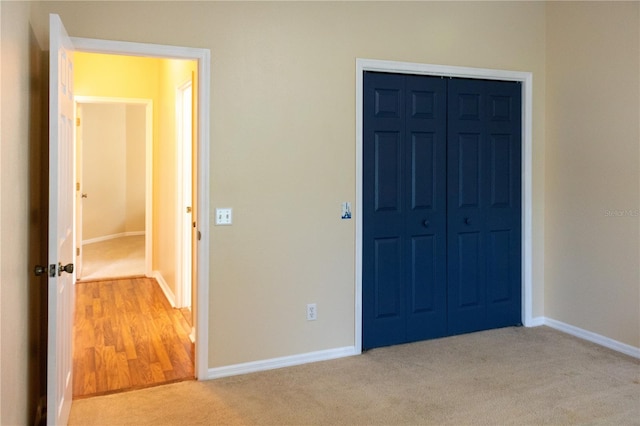 unfurnished bedroom with a closet and light colored carpet