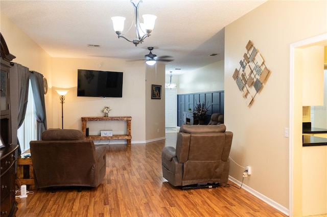 living room with ceiling fan with notable chandelier and hardwood / wood-style flooring