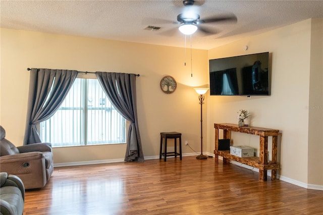 interior space with ceiling fan, a textured ceiling, and hardwood / wood-style flooring