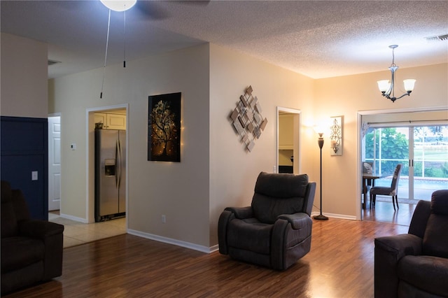 living room featuring a textured ceiling, wood-type flooring, and a notable chandelier