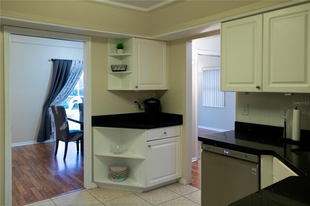 kitchen featuring stainless steel dishwasher, white cabinetry, light hardwood / wood-style flooring, and tasteful backsplash