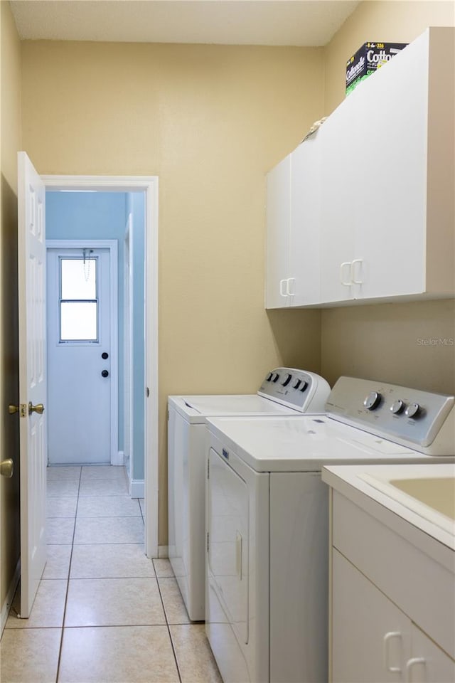 washroom featuring cabinets, light tile patterned floors, and washing machine and clothes dryer