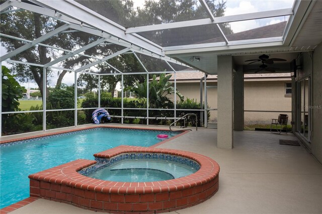 view of pool featuring an in ground hot tub, a patio, glass enclosure, and ceiling fan