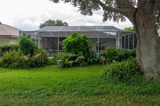 rear view of house with a yard and glass enclosure