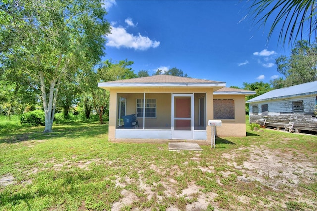 back of property featuring a lawn and a sunroom