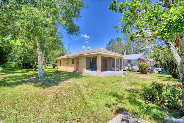 317 C St, Lake Wales, FL 33853 - rear view of house with a sunroom, a lawn, and stucco siding