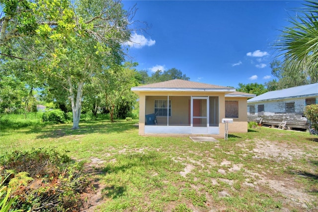317 C St, Lake Wales, FL 33853 - back of house featuring stucco siding, a sunroom, and a lawn