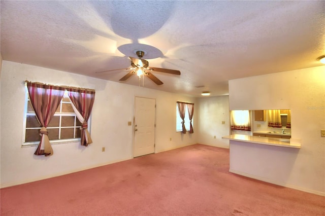 unfurnished living room featuring ceiling fan, carpet flooring, and a textured ceiling