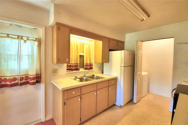 kitchen featuring white fridge, light tile patterned floors, sink, and washer and dryer