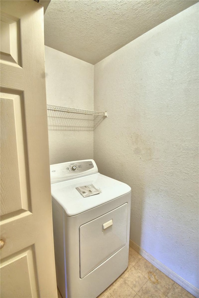 washroom with light tile patterned flooring, a textured ceiling, and washer / dryer