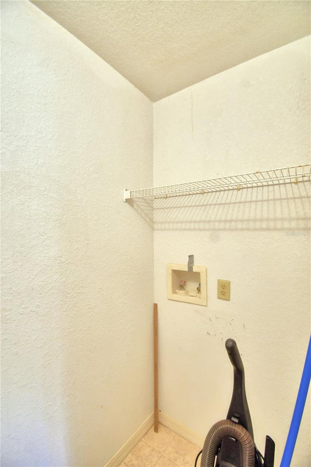 laundry area featuring a textured ceiling, light tile patterned floors, and washer hookup