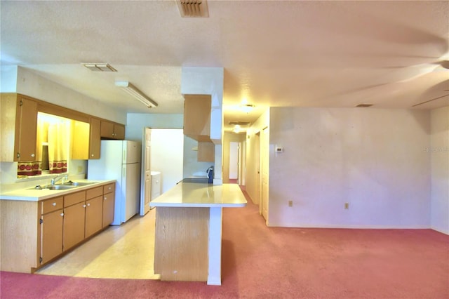 kitchen featuring sink, light carpet, kitchen peninsula, and white refrigerator