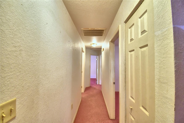 hallway with a textured ceiling and carpet flooring