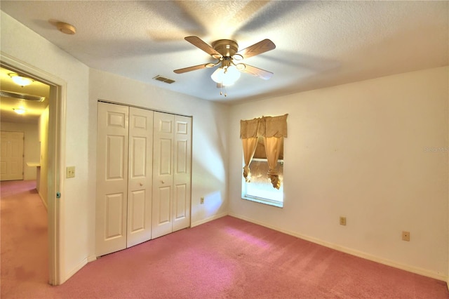 unfurnished bedroom with a textured ceiling, carpet, a closet, and ceiling fan