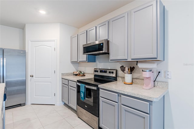 kitchen with gray cabinetry, appliances with stainless steel finishes, and light tile patterned floors