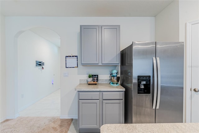 kitchen with gray cabinetry, stainless steel refrigerator with ice dispenser, and light tile patterned floors