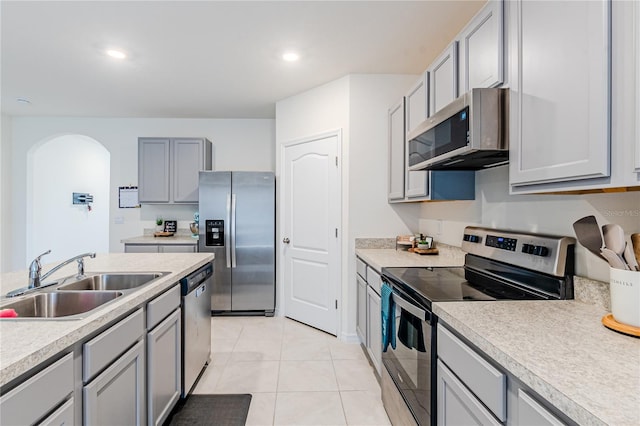 kitchen with appliances with stainless steel finishes, sink, light tile patterned floors, and gray cabinets