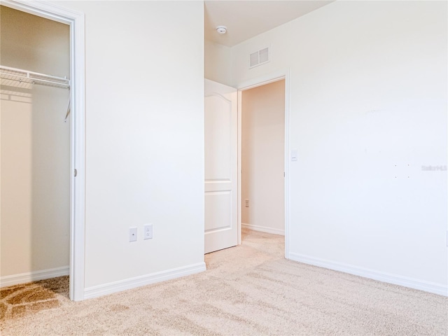 unfurnished bedroom featuring a closet and light colored carpet