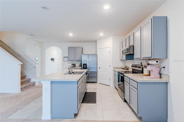 kitchen featuring a center island with sink, stainless steel appliances, gray cabinetry, light tile patterned floors, and sink