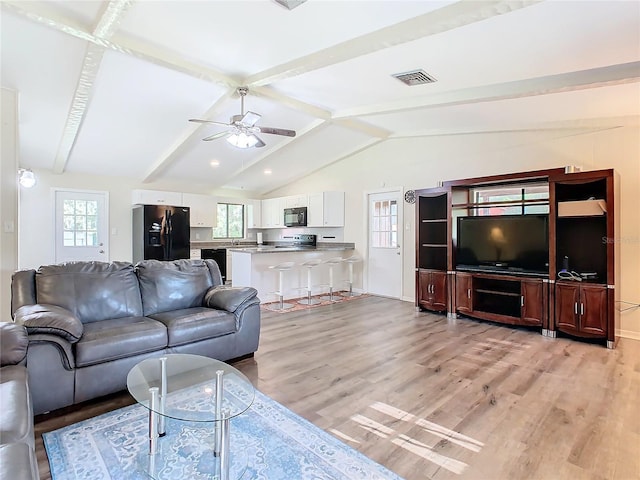 living room with light wood-type flooring, visible vents, ceiling fan, and lofted ceiling with beams