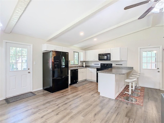 kitchen with vaulted ceiling with beams, black appliances, a peninsula, and light wood-style floors