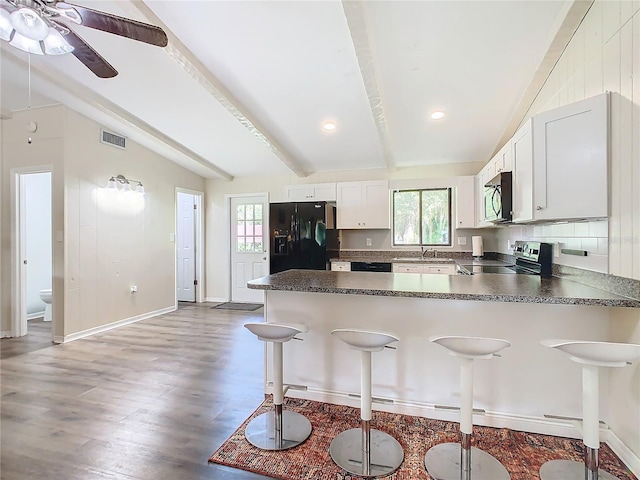 kitchen featuring lofted ceiling with beams, dark countertops, a peninsula, and stainless steel appliances