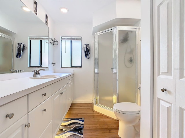 bathroom featuring toilet, a stall shower, wood finished floors, and vanity