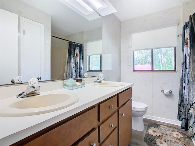 full bath with double vanity, a sink, toilet, and baseboards