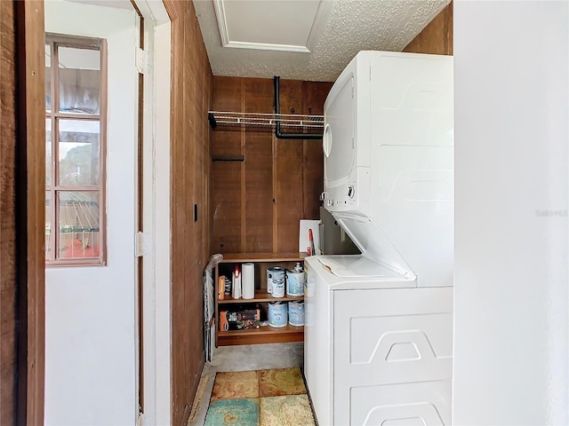 clothes washing area with stacked washer and clothes dryer, a textured ceiling, and laundry area