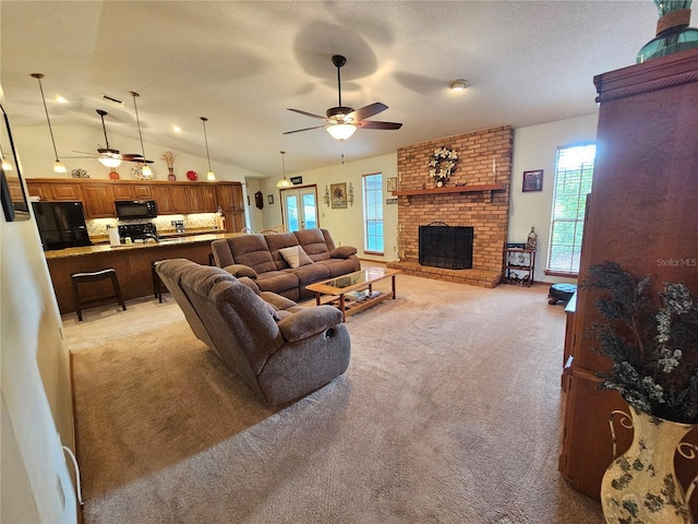 living room featuring ceiling fan, a fireplace, light carpet, and vaulted ceiling