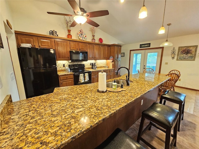 kitchen featuring sink, backsplash, lofted ceiling, a kitchen bar, and black appliances