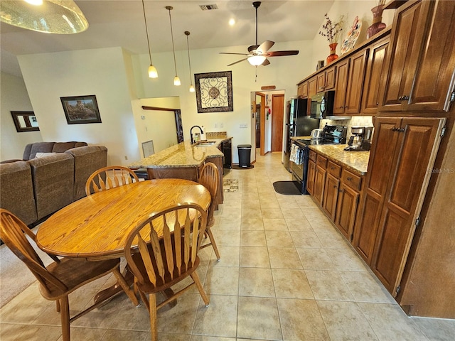 kitchen featuring light stone counters, a kitchen island with sink, black appliances, high vaulted ceiling, and hanging light fixtures