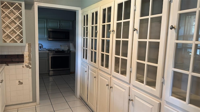 kitchen featuring white cabinets, stainless steel appliances, and light tile patterned floors